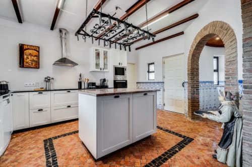 Modern villa kitchen at Quinta do Águas in Lagoa with white cabinetry, terracotta tile floors, and arched brick entryway
