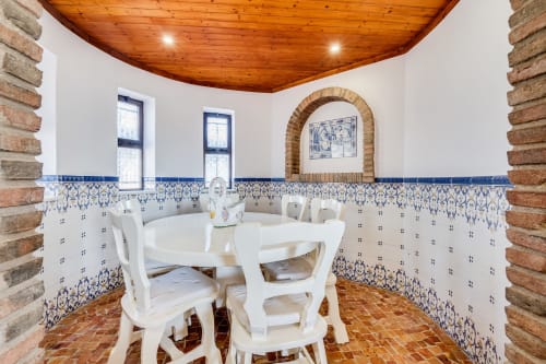 Quinta do Águas villa dining room with blue and white Portuguese tiles, wooden ceiling, arched alcove, and round white table