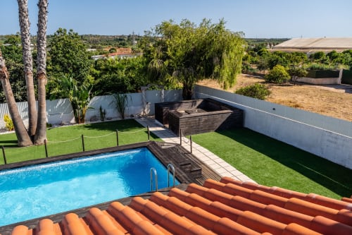Private pool and terrace at Quinta do Águas villa in Lagoa, Portugal, with manicured lawn and rustic barbecue area.