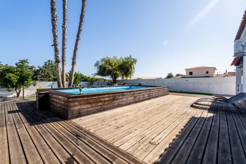 Wooden deck with above-ground swimming pool and palm trees at Quinta do Águas villa in Lagoa, Portugal
