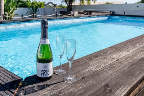 Posi Tivo champagne bottle and two glasses on wooden poolside deck at Quinta do Águas villa in Lagoa, Portugal
