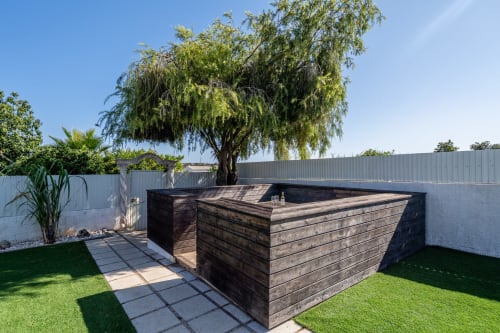 Modern wooden-style pool structure in sunny Lagoa villa garden with mature weeping tree and manicured lawn