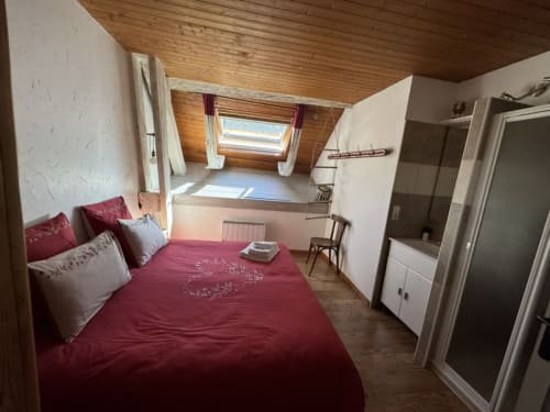 Chambre mansardée douillette avec literie bordeaux au gîte LA JUMENT VERTE à Trévignin, fenêtre de toit, plafond en bois