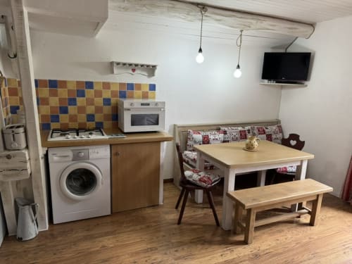 Open-plan cottage kitchen and dining area at La Jument Verte with equipped kitchenette, dining table, and TV