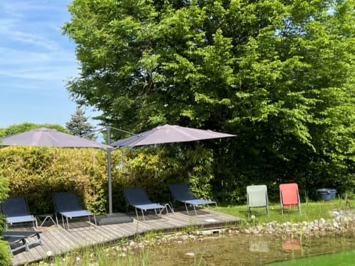 Terrasse waterfront à LA JUMENT VERTE avec transats, parasols en porte-à-faux et vue sur le bassin à Trévignin, France.