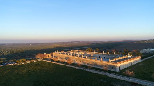 Vista aerea della Biomasseria Lama di Luna, un'antica masseria in pietra ad Andria, Italia, circondata dalla campagna al tramonto