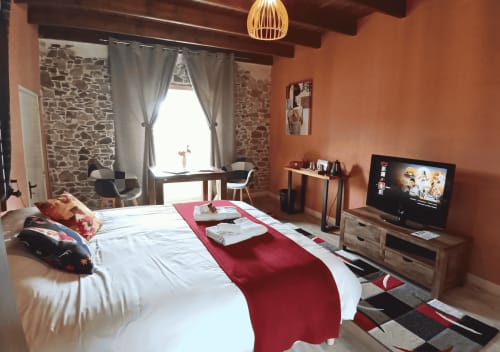 Sakura-Schlafzimmer im La Synchronicité BnB mit Terrakottawänden, Steinelementen, Kingsize-Bett, TV und Gartenblick in Saint