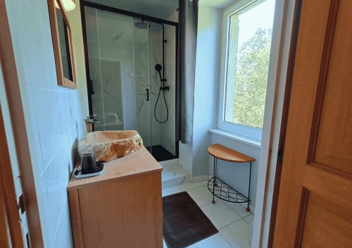 Modern badkamer in La Synchronicité B&B met wastafel, glazen douchecabine en raam met uitzicht op de tuin in Saint Sauveur