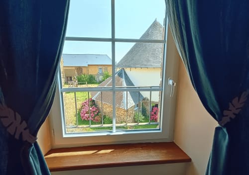 Uitzicht vanuit Écureuil Studio van B&B La Synchronicité: Franse platteland met stenen gebouwen en roze bloemen