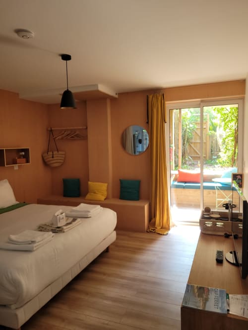 Dormitorio Urban Mood en Le Lodge du Cap Ferret con paredes naranjas, cama blanca, acceso a vista del jardín y comodidades modernas