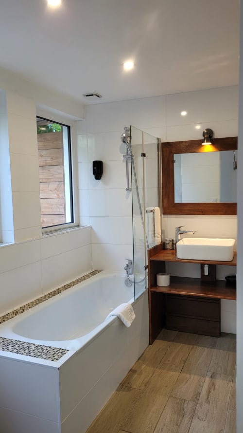 Baño moderno en la habitación Urban Mood de Le Lodge du Cap Ferret con bañera de inmersión, ducha lluvia, tocador de madera y vistas al jardín