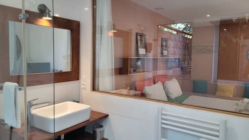 Cuarto de baño moderno en Le Lodge du Cap Ferret con lavabo tipo recipiente, ducha de cristal, espejo y vista al jardín desde el dormitorio