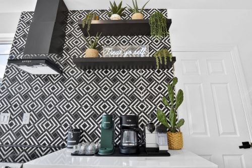 Coffee bar setup in Malkita Aria villa with black shelving, plants, and geometric patterned backsplash at Woodbury property