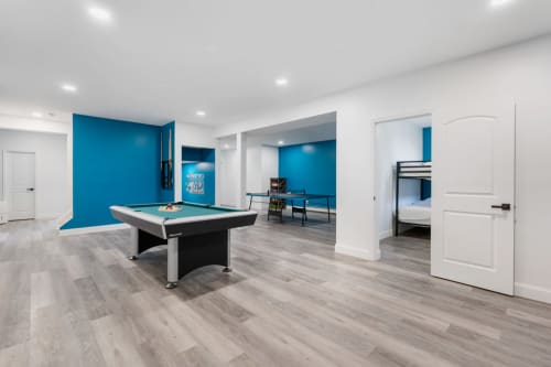 Modern recreation room with pool table, ping pong, blue accent walls, and open layout in Malkita Aria villa, Woodbury