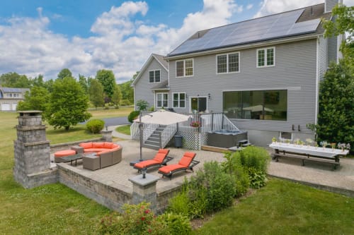 Modern mountainview villa in Woodbury with solar panels, multi-level deck, fire pit, and outdoor lounge seating on patio.