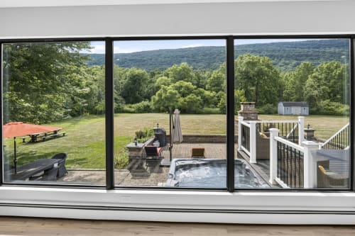 Mountain view from villa windows at Malkita Aria, showing patio with hot tub, deck, outdoor furniture, and forested hills in