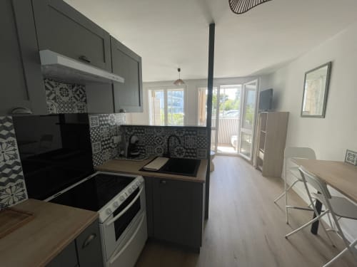 Cuisine moderne avec dosseret géométrique noir et blanc, électroménagers inox, comptoirs en bois, coin repas et baies vitrées