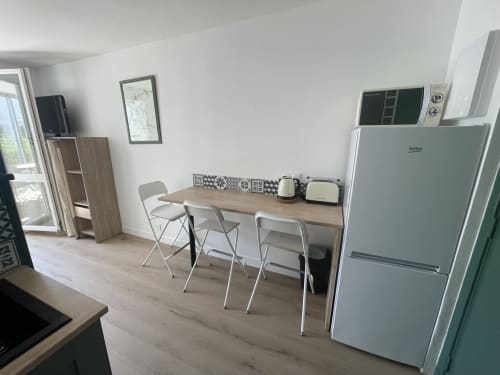 Kitchenette moderne avec table à manger, réfrigérateur blanc et micro-ondes en acier inoxydable à l'appartement Studio L'île verte,