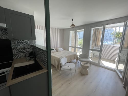 Studio moderne à Roscoff avec kitchenette, lit, coin salon et baies vitrées donnant sur la ville