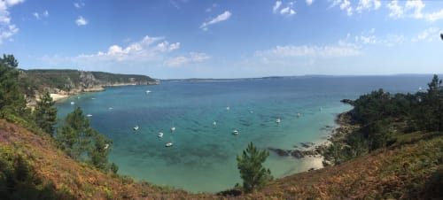 Baie turquoise avec bateaux amarrés, plage de sable fin et falaises couvertes de pins près de Roscoff, Finistère