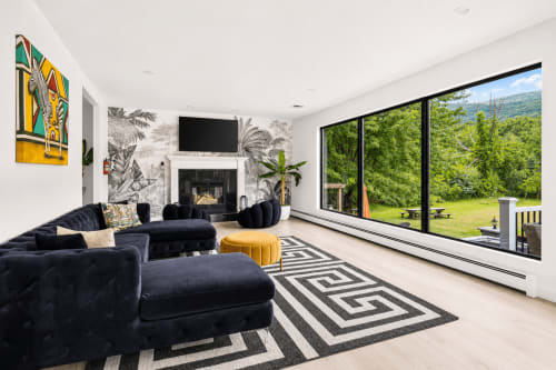 Modern mountain view villa living room with black sectional sofa, fireplace, and large windows overlooking green landscape at