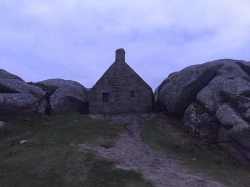 Petite maison en pierre nichée parmi les rochers de granit en Finistère rural, Bretagne, au crépuscule