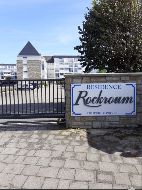 Portail d'entrée de la Résidence Rockroum avec pancarte, complexe d'appartements à Roscoff aux bâtiments en pierre et tour