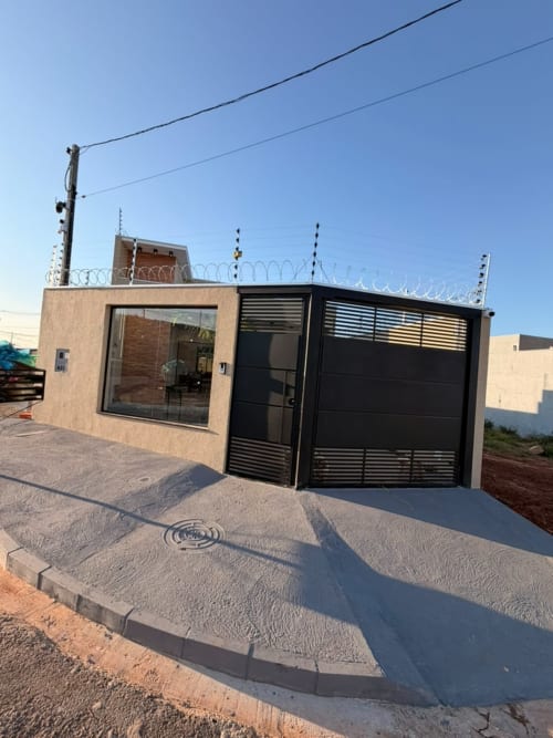 Casa Coqueiros em Maringá com pátio, portão de metal preto, fachada de tijolos e acesso por escada espiral no telhado