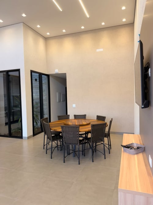Sala de jantar moderna na pousada Casa Coqueiros em Estadia e Alegria, Maringá, com mesa redonda e cadeiras de vime preto