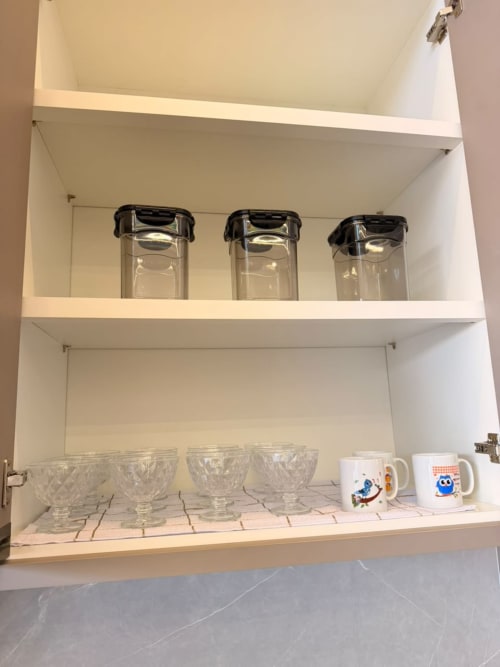 Armário de cozinha com potes de armazenamento, copos e canecas na pousada Casa Coqueiros, Maringá