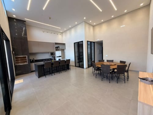 Cozinha integrada moderna e área de refeições na pousada Casa Coqueiros em Maringá com eletrodomésticos em aço inoxidável