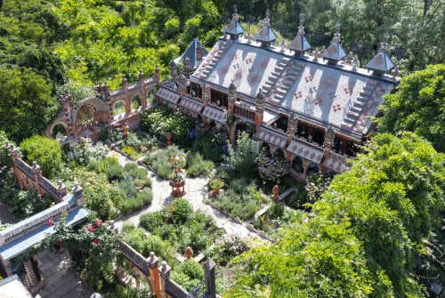 Vue aérienne de l'hôtel boutique Micro Palaces à Vaulx, France, avec son architecture en briques ornementales et ses jardins luxuriants