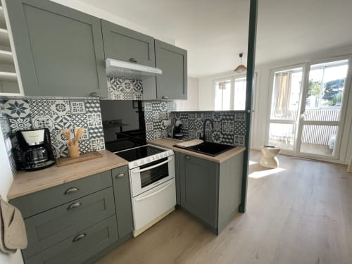 Cuisine moderne verte avec carrelage motifs, plans en bois et vue sur mer à Parenthèse En Finistère, Roscoff