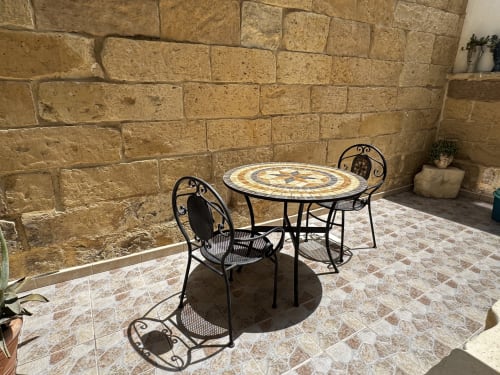 Sedute esterne del patio con sedie in ferro battuto e tavolo a mosaico presso l'hotel HABITARE Lecce a Salento, Italia
