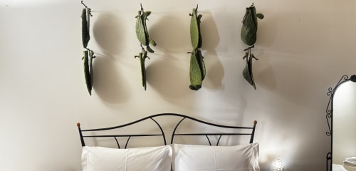 Letto con cuscini bianchi all'HABITARE Lecce, decorazione di baccelli di piselli secchi sulla parete beige sopra la testata