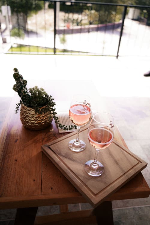 Dos copas de vino rosé en bandeja de madera con cactus en maceta, vista de patio al aire libre en Hotel El Porvenir, Querétaro