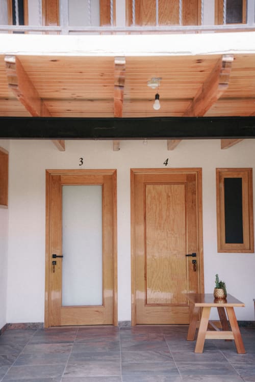 Puertas y ventanas de madera en la entrada del Hotel El Porvenir con pequeña planta en banco, Querétaro México