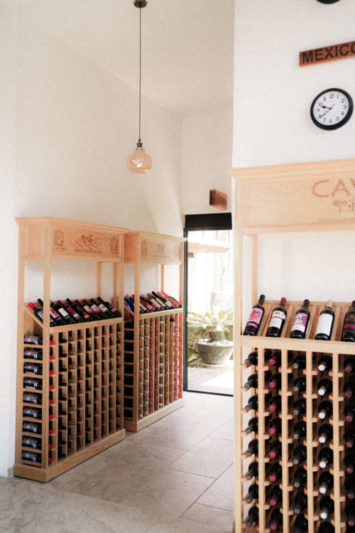 Bodega del Hotel El Porvenir en Querétaro, México, con estantes de madera para vinos e iluminación colgante