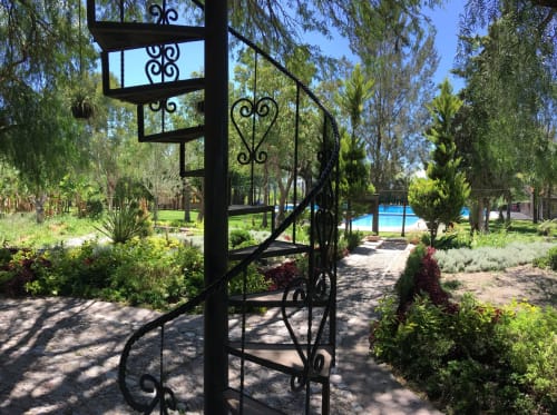 Pérgola negra ornamental en frondoso jardín del Hotel El Porvenir, Querétaro, con piscina y paisajes verdes