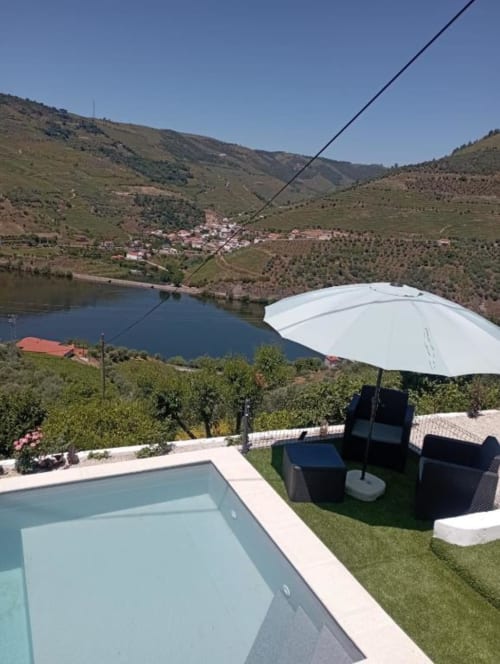 Terraço da piscina Tomás Barqueiro com vista para o vale do Douro em Folgosa, com guarda-sol branco e vistas do rio