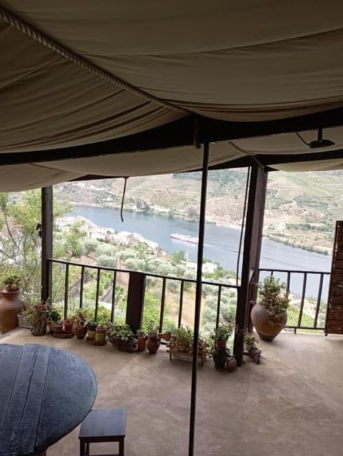 Terraço sombreado em Tomás Barqueiro com plantas em vasos, grades e vistas do vale do rio Douro em Folgosa