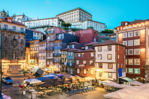 Icônico bairro do Porto ao entardecer com edifícios coloridos, guarda-chuvas e cafés - localização AgapeStay Porto