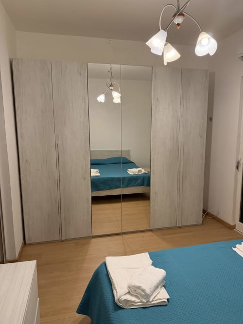 Camera moderna a Zappy Domus a Castellaneta Marina con armadio a specchi, letto blu e illuminazione contemporanea