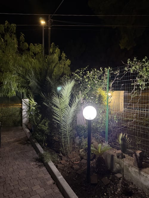 Terrazza giardino notturna di Zappy Domus con lampada luminosa, piante tropicali e recinzione verde a Castellaneta Marina