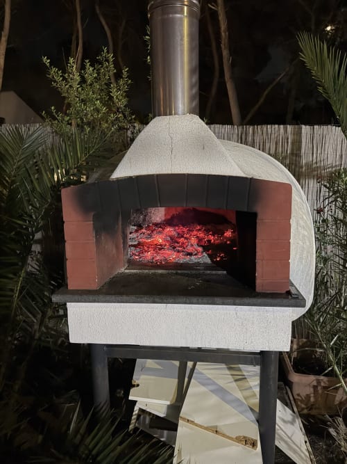 Forno a legna esterno presso Zappy Domus B&B a Castellaneta Marina, illuminato di notte dalle braci rosse
