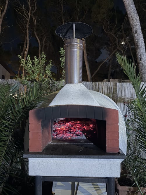 Forno a legna splendente di notte sulla terrazza dell'appartamento Zappy Domus a Castellaneta Marina, Italia