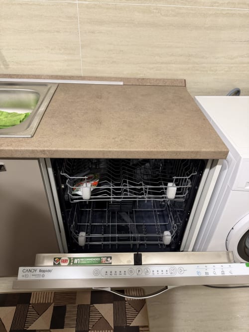 Lavastoviglie incassata nell'appartamento Tereskova di Zappy Domus, Castellaneta Marina, con porta aperta che mostra i cestelli e il detersivo Fairy