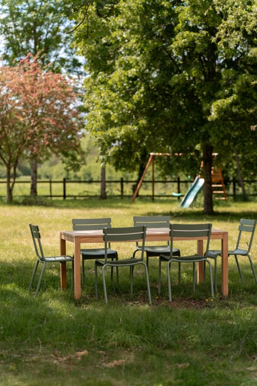 Espace de restauration extérieure à Maisons Noisette avec table en bois, chaises métalliques et aire de jeux dans la campagne française