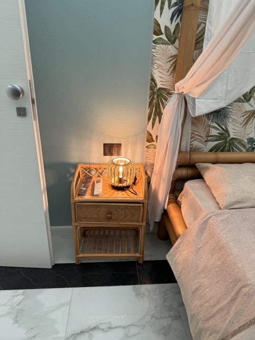 Angolo camera da letto a Zappy Domus B&B di Taranto con comodino in legno, lampada d'atmosfera e carta da parati tropicale