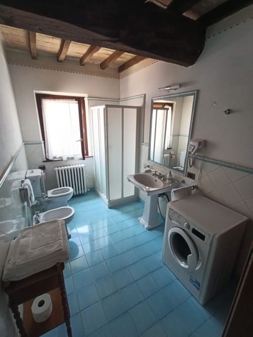 Spacious bathroom at Agriturismo Aggazzotti with blue tile floors, dual sinks, shower, washing machine, and rustic wooden